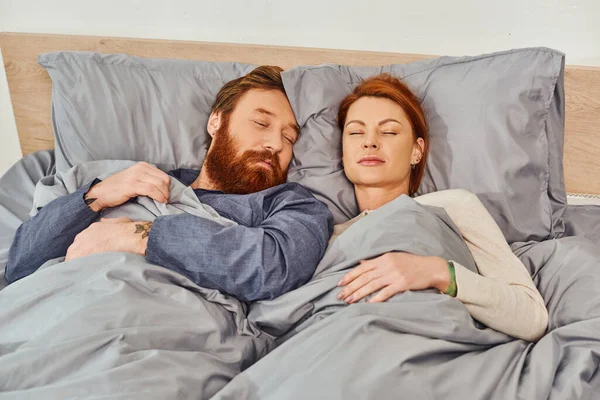 Parents alone at home, quiet house, redhead husband and wife sleeping in cozy bedroom, bearded man and carefree woman relaxing on weekends, day off, tattooed people, closed eyes — Stock Photo