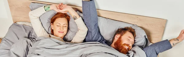 Quiet house, parents alone at home, redhead husband and wife in cozy bedroom, bearded man and carefree woman relaxing on weekends, day off, wake up, tattooed, closed eyes, enjoy, top view, banner — Stock Photo