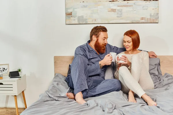 Morning rituals, day off without kids, redhead husband and wife, quality time, happiness, bearded man and woman holding cups of coffee, parents alone at home, lifestyle, adult leisure, interior — Stock Photo
