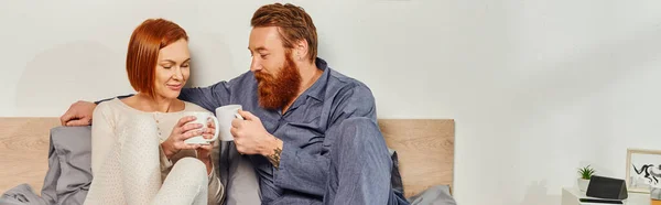 Morning rituals, day off without kids, redhead husband and wife, quality time, happiness, bearded man and woman holding cups of coffee, parents alone at home, lifestyle, adult leisure, banner — Stock Photo