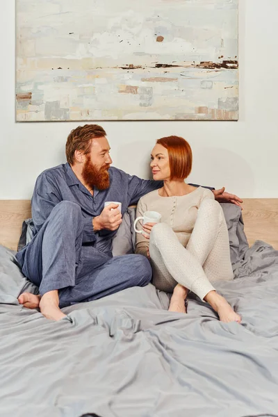 Coffee and conversation, morning rituals, quality time, day off without kids, redhead and happy husband and wife, bearded man and woman holding cups, parents alone at home, lifestyle — Stock Photo