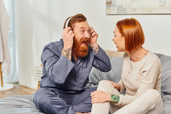 Music enjoyment, excited and bearded man, day off without kids, redhead husband and wife, bearded man in wireless headphones, cheerful parents alone at home, modern lifestyle, relationship — Stock Photo