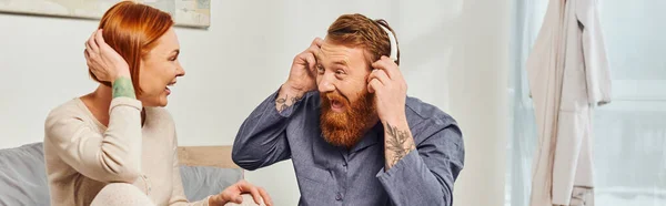 Felicidade, homem animado e barbudo, dia de folga sem filhos, marido e esposa ruiva, homem barbudo em fones de ouvido sem fio, pais alegres sozinhos em casa, estilo de vida moderno, ouvir música, banner — Fotografia de Stock