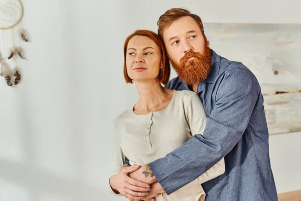 Married couple hugging in cozy bedroom, day off without kids, redhead husband and wife, enjoying time together, weekends together, tattooed, bonding, parents alone at home — Stock Photo