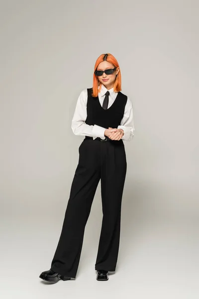 Black and white clothes, business fashion, asian woman with dyed hair posing in dark sunglasses on grey background, full length, generation z, business casual, confident and successful — Stock Photo