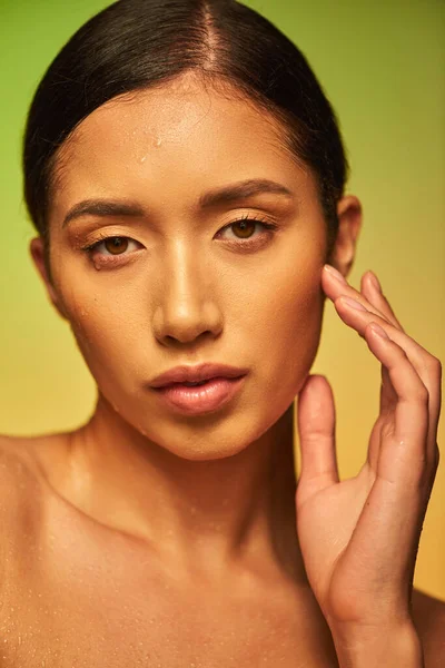 Wassertropfen, Nahaufnahme einer jungen asiatischen Frau mit feuchter Haut, die in die Kamera auf grünem Hintergrund blickt, Hautfeuchtigkeit, braune Augen, Schönheitskampagne, Perfektion, Wohlbefinden, konzeptionelle — Stockfoto