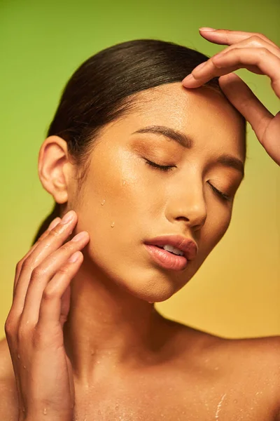 Капли воды на лице, крупным планом молодой азиатской женщины с закрытыми глазами и влажной кожей на зеленом фоне, увлажнение кожи, косметическая кампания, совершенство, оздоровительный, концептуальный — стоковое фото