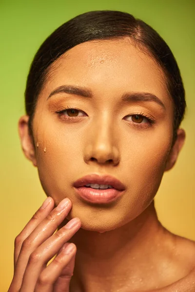 Wassertropfen im Gesicht, Nahaufnahme einer jungen asiatischen Frau mit feuchter Haut vor der Kamera auf grünem Hintergrund, Hautfeuchtigkeit, Gesichtspflegekampagne, Perfektion, Wohlbefinden, konzeptionelle — Stockfoto