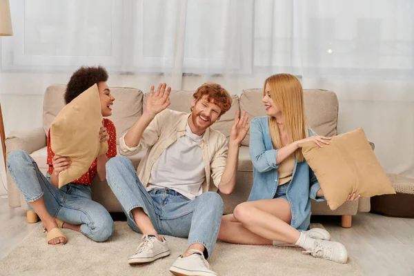 Polygamy, acceptance and bonding, group relationship, happy multicultural women and bearded man fighting with pillows, open relationship, diversity and bonding, non monogamy, three people — Stock Photo