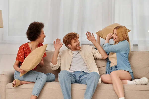 Polyamorous family, group relationship, cheerful multicultural women and bearded man fighting with pillows, open relationship, diversity and bonding, non monogamy, three people — Stock Photo