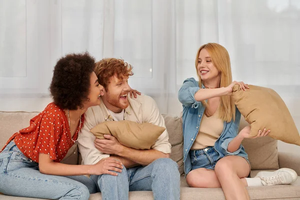 Polyamorous family, group relationship, positive multicultural women and bearded man fighting with pillows, open relationship, diversity in relationships, non monogamy, three people — Stock Photo