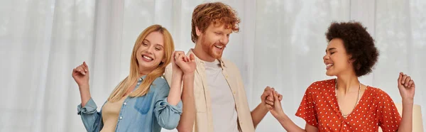 Полігамія, щасливі мультикультурні жінки і бородатий чоловік тримає руки, розважається, танцює у вітальні, кохання і різноманітність у відносинах, сучасна сім'я, прийняття і зв'язок, банер — стокове фото