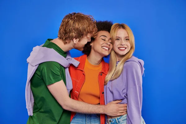 Conceito poliamor, mulheres multiculturais positivas e ruiva homem abraçando em fundo azul, fotografia de estúdio, diversidade cultural, poligamia, família moderna, roupas coloridas — Fotografia de Stock