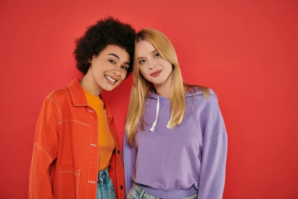 Cultural diversity, happy multicultural women looking at camera on coral background, blonde and brunette, diverse friends, sisterhood, friendship goals, studio shot, multiracial people — Stock Photo