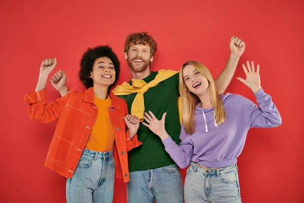Polyamorous concept, polygamy lovers, young man and multicultural women celebrating on coral background, studio shot, denim fashion, love triangle, bonding and acceptance — Stock Photo