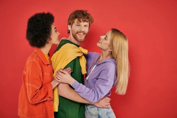 Polygamy concept, interracial lovers showing hugging each other on coral background, cultural diversity, polyamorous, happy multiethnic people, looking at camera, open relationship — Stock Photo