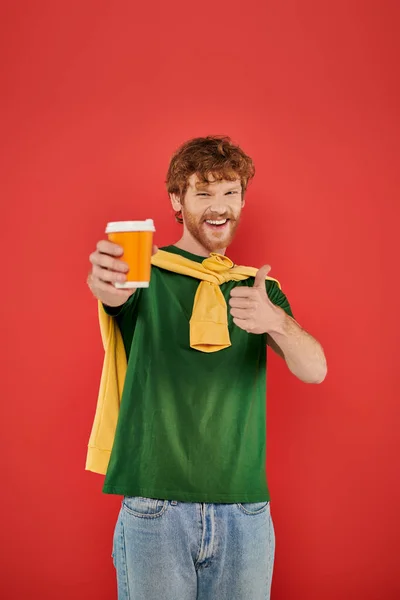 Morning coffee, energy, like, redhead man with beard and curly hair holding paper cup on coral background, vibrant colors, male fashion, takeaway drink, male portrait, hot beverage — Stock Photo