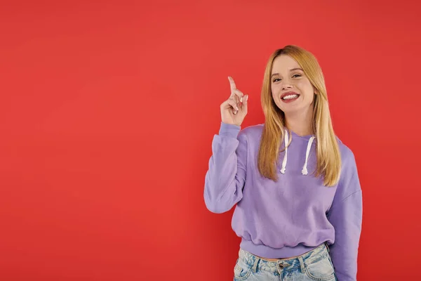 Hand gesture, youthful fashion, blonde young woman in casual attire showing something on coral background, happiness, looking at camera, vibrant colors, fashion forward, modern individual, model — Stock Photo