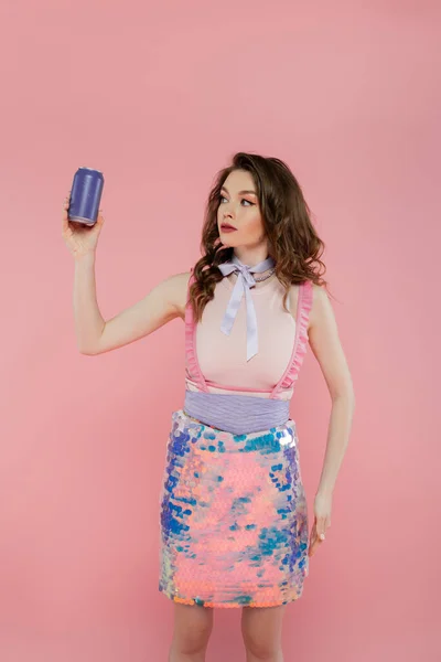 Doll concept, attractive young woman with wavy hair holding soda can with carbonated drink, standing on pink background, fashion model in stylish outfit, femininity, doll pose, advertisement — Stock Photo