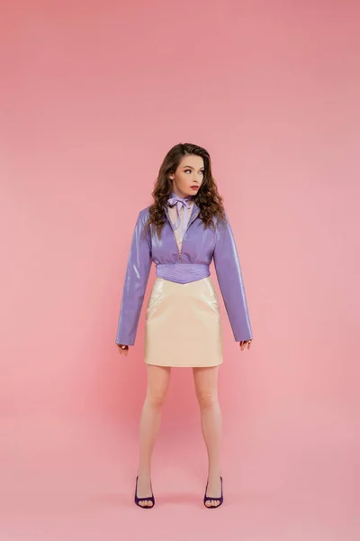 Гламур, красивая молодая женщина смотрит в сторону, модный наряд, привлекательная девушка в фиолетовой куртке и юбке стоя на розовом фоне, студия выстрел, концептуальный, полная длина модной модели — стоковое фото