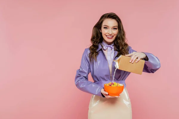 Concept photography, doll like, happy woman with wavy hair holding bowl with corn flakes, pouring milk from carton box, tasty breakfast, posing on pink background, stylish purple jacket — Stock Photo