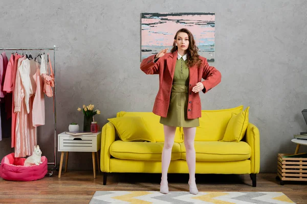 Concept photography, full length of woman acting like a doll, gesturing unnaturally and standing near yellow couch, well dressed and beautiful, modern house interior, role play, doll life — Stock Photo