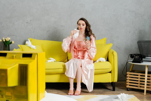 Emotional stress, sad woman with smudged mascara sitting on yellow couch, housewife with crying eyes holding napkin and cocktail, watching tv, depressed and heartbroken wife at home — Stock Photo
