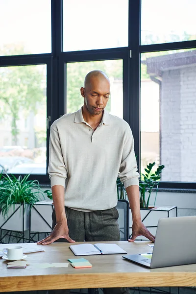 Chronic illness, bold african american businessman with eye syndrome looking at laptop on desk, myasthenia gravis, dark skinned office worker, inclusion, diversity in society, — Stock Photo