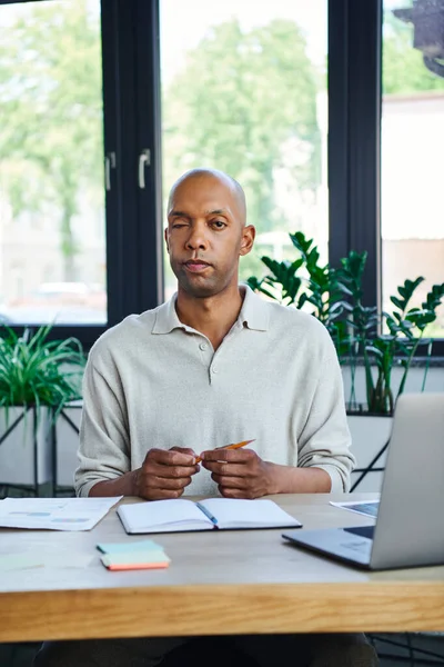 Ptosis syndrome, bold african american businessman with eye syndrome looking at camera near laptop on desk, myasthenia gravis, dark skinned office worker, diversity and inclusion, smart casual — Stock Photo