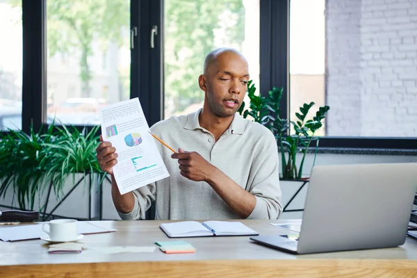 Myasthenia gravis, bold african american businessman with eye syndrome showing graphs during video call on laptop, dark skinned office worker with ptosis , diversity and inclusion, presentation — Stock Photo