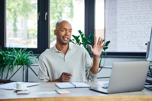 Myasthenia gravis, bold african american businessman with eye syndrome waving hand during video call on laptop, dark skinned office worker with ptosis syndrome, diversity and inclusion — Stock Photo