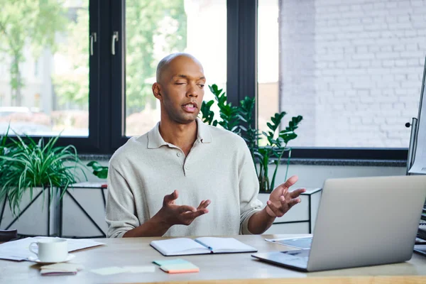 Myasthenia gravis, bold african american businessman with eye syndrome gesturing while discussing project during video call, dark skinned office worker with ptosis syndrome, diversity and inclusion — Stock Photo