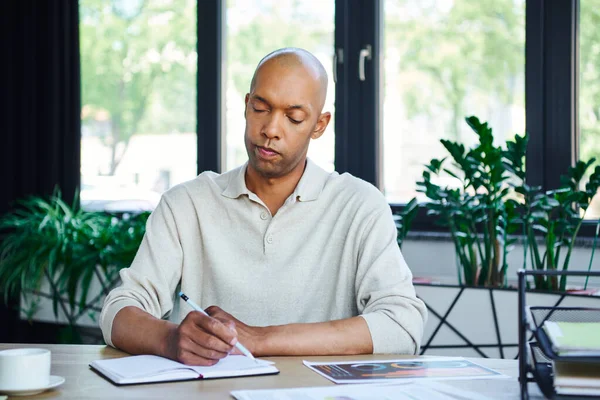 Man with ptosis syndrome taking notes, bold african american businessman at work, dark skinned office worker with myasthenia gravis disease, diversity and inclusion — Stock Photo