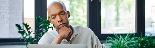 Ptosis, eye syndrome, pensive african american businessman looking at laptop, bold and dark skinned office worker with myasthenia gravis disease, diversity and inclusion, banner — Stock Photo