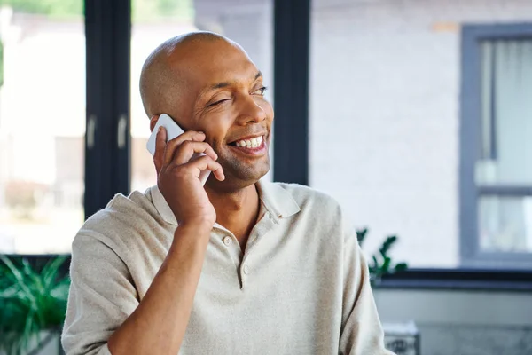 Myasthenia gravis disease, bold african american man at work, cheerful and dark skinned office worker with ptosis syndrome talking on smartphone, inclusion, corporate culture — Stock Photo