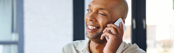Myasthenia gravis disease, bold african american man at work, cheerful and dark skinned office worker with ptosis syndrome talking on smartphone, inclusion, corporate culture, banner — Stock Photo