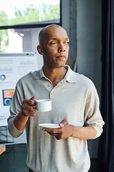 Chronic illness, inclusion, african american man with myasthenia gravis disease holding cup of coffee, bold and dark skinned office worker with ptosis syndrome having coffee break — Stock Photo