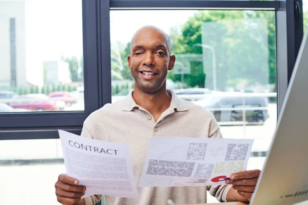 Inclusion, happy african american man with myasthenia gravis disease holding contract, dark skinned office worker in casual attire looking at camera, ptosis syndrome, professional headshots — Stock Photo