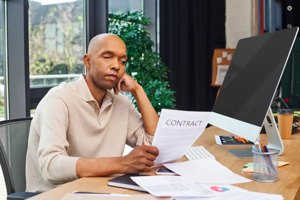 Inclusion, african american man with myasthenia disease looking at contract, dark skinned office worker in casual attire sitting at desk, monitor, smartphone, documents and graphs, ptosis syndrome — Stock Photo