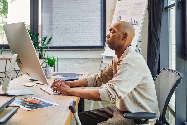 Inclusion, homme afro-américain avec myasthénie grave au travail, travailleur de bureau gras et à la peau foncée tapant sur le clavier et à l'aide d'un ordinateur, en regardant moniteur, graphiques et papeterie sur le bureau — Photo de stock