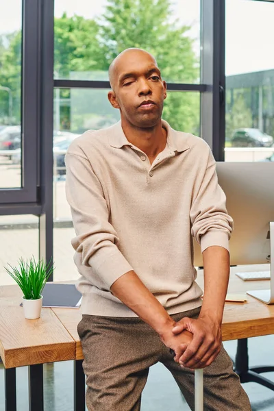 Inclusion, bold african american businessman with myasthenia gravis syndrome, standing with walking cane near computer monitor on working desk, dark skinned office worker in casual attire — Stock Photo