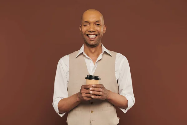Inclusion, homme afro-américain heureux et audacieux avec syndrome de myasthénie grave, debout avec tasse en papier, homme à la peau foncée avec une maladie chronique sur fond brun, café à emporter — Photo de stock