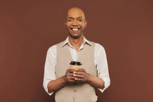 Inclusion, happy and bold african american man with myasthenia gravis syndrome, standing with paper cup, dark skinned man with chronic disease on brown background, coffee to go — Stock Photo