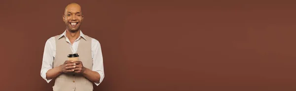 Включение, счастливый и смелый африканский американец с синдромом миастении грависа, стоящий с бумажной чашкой, темнокожий мужчина с хронической болезнью на коричневом фоне, кофе с собой, баннер — стоковое фото