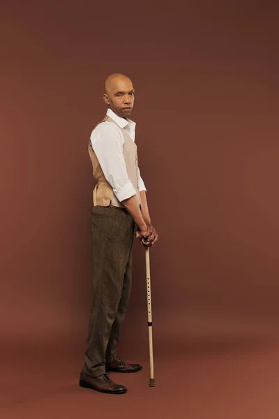 Inclusion, myasthenia gravis syndrome, bold african american man standing with walking stick, looking at camera, dark skinned, real people, neurological disorder, physical impairment, full length — Stock Photo