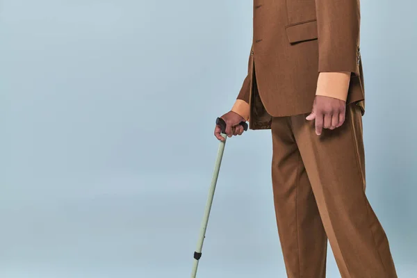 Real people, cropped view of african american man leaning on walking cane on grey background, dark skinned person in suit, diversity and inclusion, difficulty walking, autoimmune disease — Stock Photo