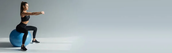 Ajuste morena esportista em preto desgaste ativo exercitando na bola de fitness em fundo cinza, banner — Fotografia de Stock