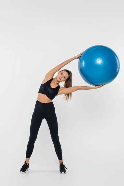 Donna che esercita con palla di stabilità e in piedi su sfondo bianco, concetto sano e in forma — Foto stock