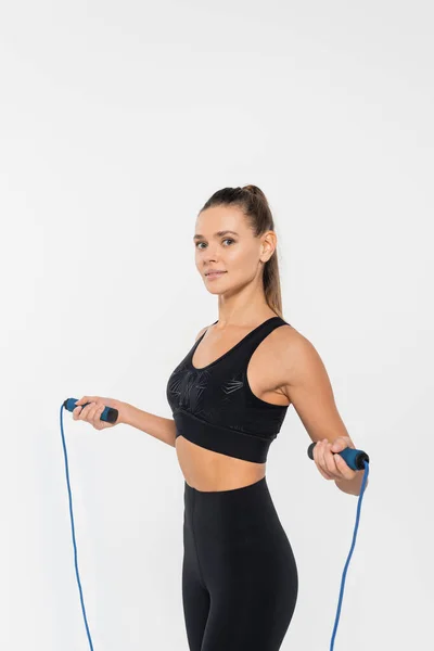 Woman in fitness clothes holding skipping rope, training isolated on white, healthy and fit concept — Stock Photo