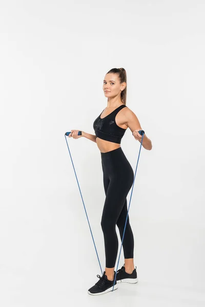 Fit woman in fitness clothes holding jump rope on white background, healthy and fit concept — Stock Photo